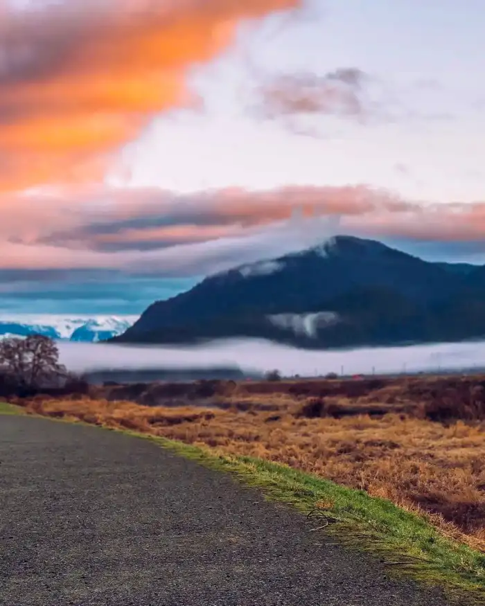 Photo Editing Road Leading To A Body Of Water With Mountains In The Background Background