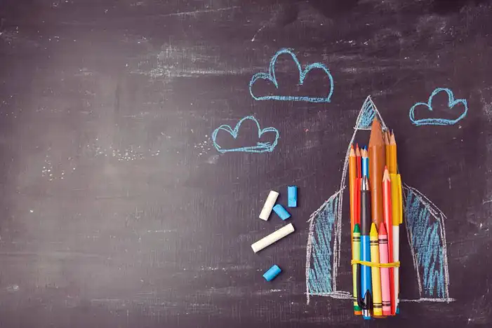 School Rocket Shaped Pencils And Crayons On A Chalkboard Background